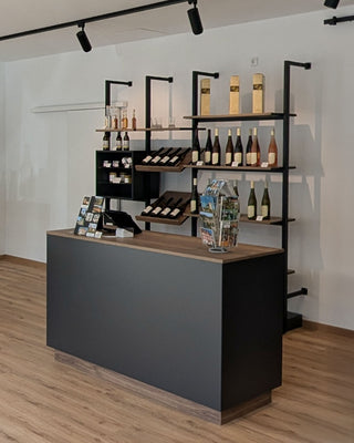 Wine display with bottles and glasses on shelves in a store setting.